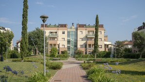 A pathway leading to a multi-story residential building with balconies and a central glass elevator. - Rosmini Serbati (Rimini)