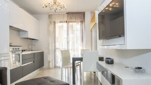 A modern kitchen with a dining area, a TV mounted above the counter, and a chandelier. - Rosmini Serbati (Rimini)