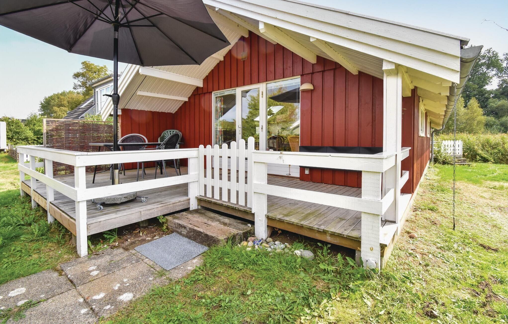 Een houten terras met een witte balustrade, een overdekte zithoek en een grote parasol.