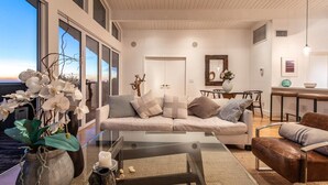 Ein modernes Wohnzimmer mit einer Couch, einem Couchtisch und Blick auf den Ozean.