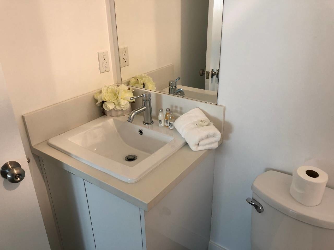 A bathroom with a sink, mirror, toilet, and a towel.