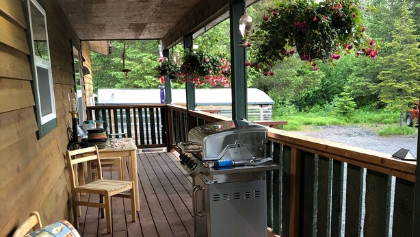 Une terrasse extérieure couverte, équipée d’un barbecue, de chaises et d’une table.