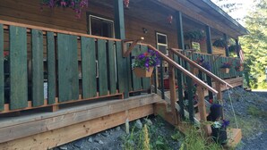 Une cabane en bois dotée d’une terrasse en bois, d’un escalier et de jardinières suspendues.