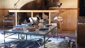 Une pièce décorée d’une tête d’ours empaillée, d’une canne à pêche et d’une table sur laquelle se trouvent des livres et une télécommande.