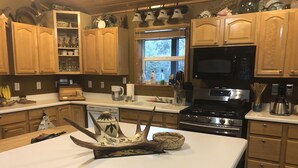 Une cuisine dotée de meubles en bois, d’un four à micro-ondes, d’une cuisinière et de divers ustensiles de cuisine.