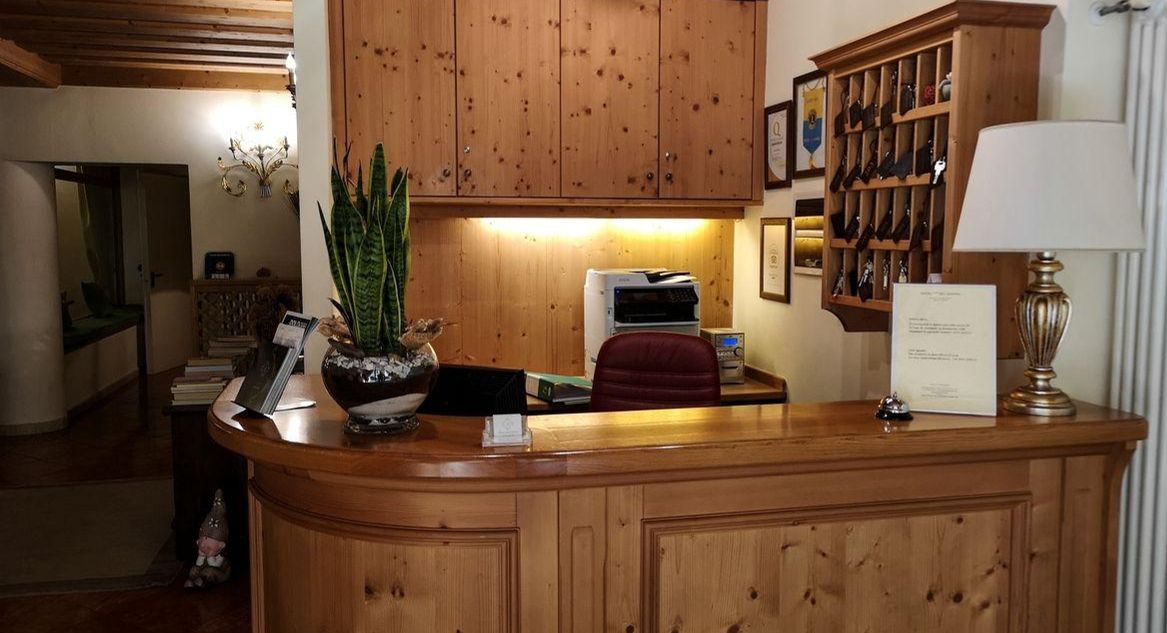 A wooden reception desk with a potted plant, a red chair, and a lamp.
