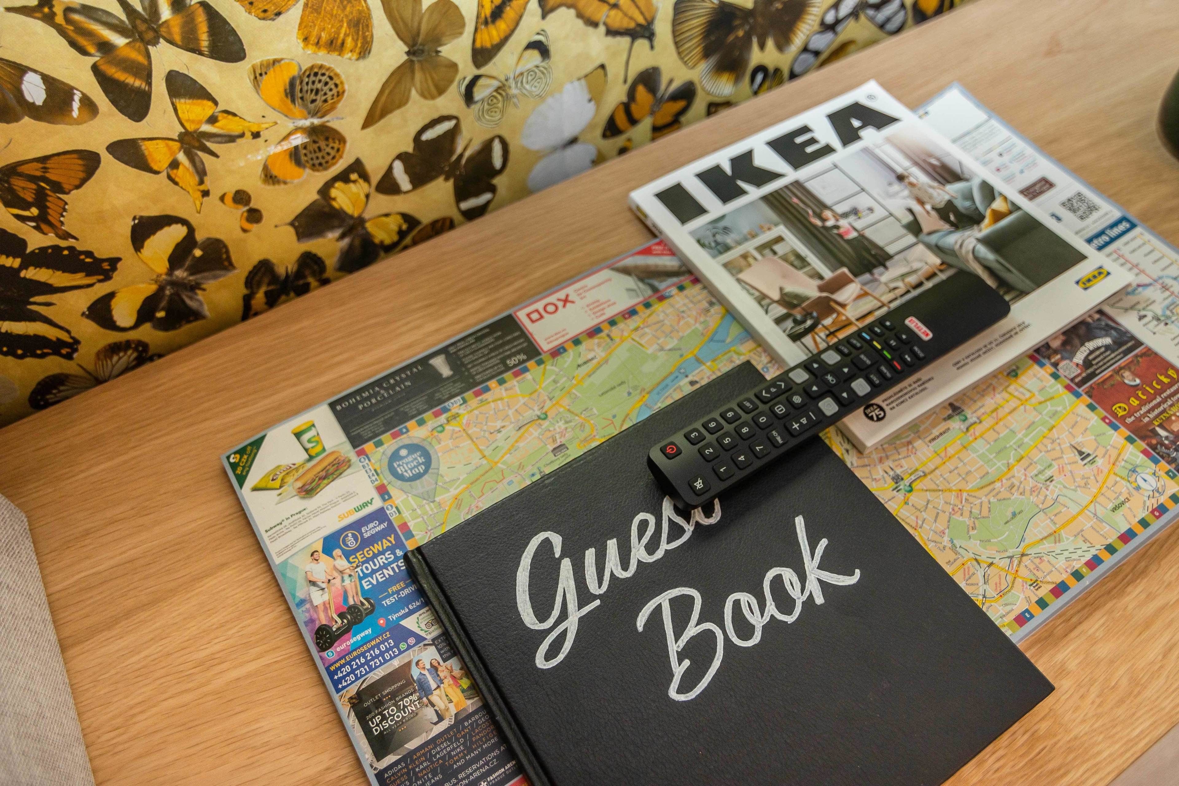 A table with a map, a magazine, a remote control, and a black book titled "Guest Book".