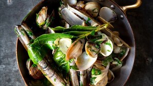 Un bol de palourdes et de moules, agrémenté d’herbes vertes.