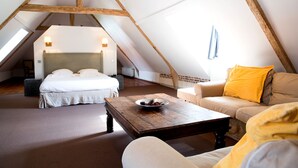 Une chambre confortable située sous les toits, avec un lit, un canapé et une table basse.