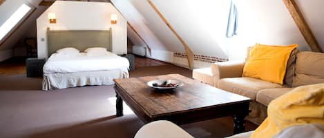 A cozy attic bedroom with a bed, a sofa, and a coffee table.