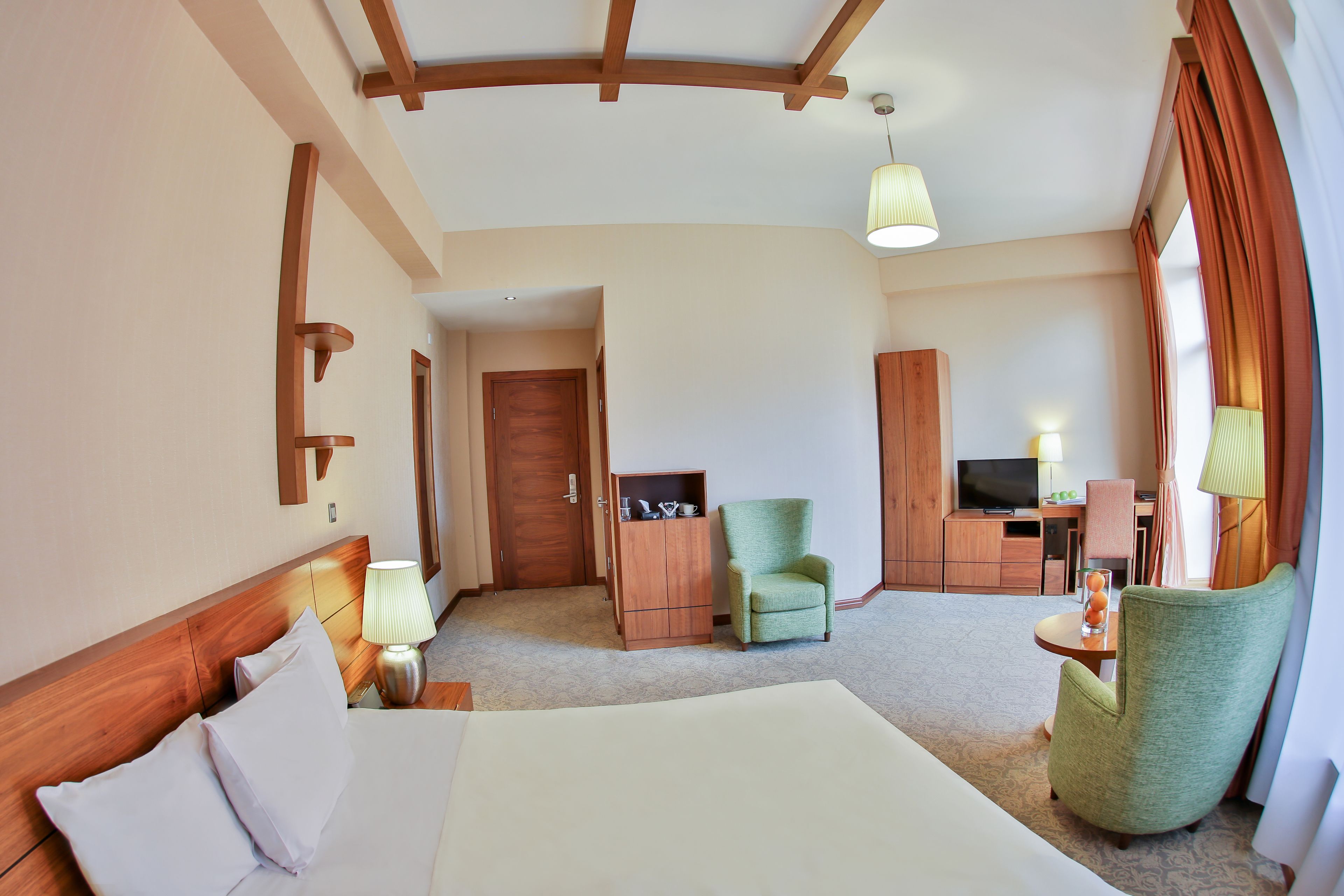 A hotel room with a large bed, a desk with a chair, a television, and a cabinet.