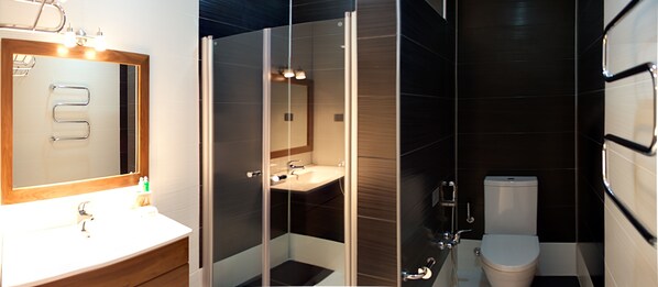 A modern bathroom with a wooden vanity, a glass shower enclosure, a sink, and a toilet.