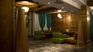 Eine geräumige Lobby mit Holzboden, grünen Sofas und einer Wand als Holzdekor.