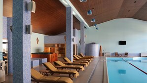 Ein Poolbereich mit Liegestühlen, einer Küche und einer gefliesten Wand.