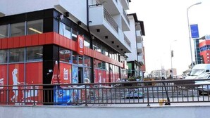 A modern building with a red and white facade, large windows, and a balcony on the upper floor. - Emerald Apartment (Pristina)