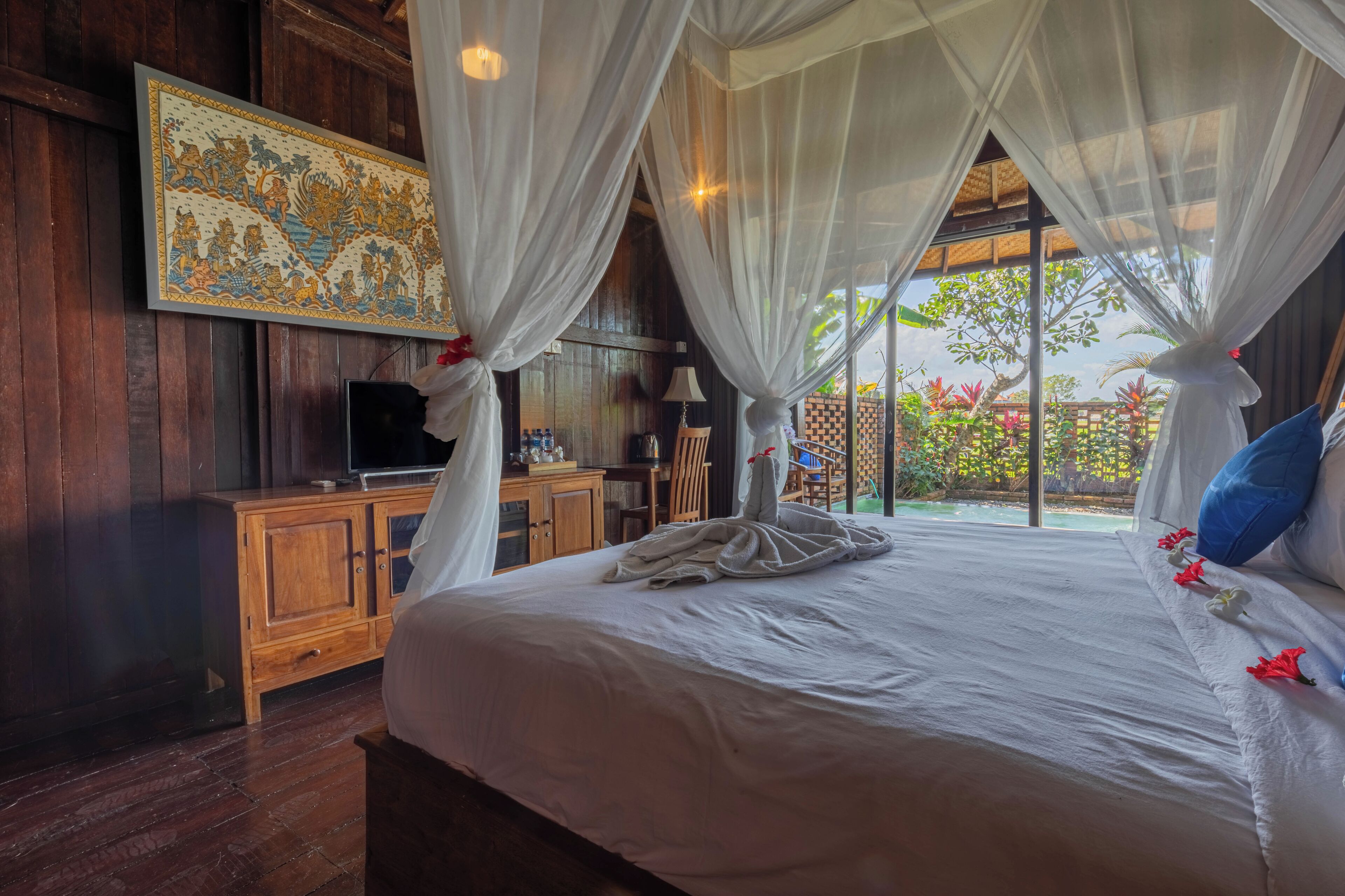 Un dormitorio con una cama grande, muebles de madera, televisión y vistas al exterior.
