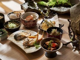 Una variedad de platos con pescado, fideos y verduras, dispuestos sobre una mesa de madera.