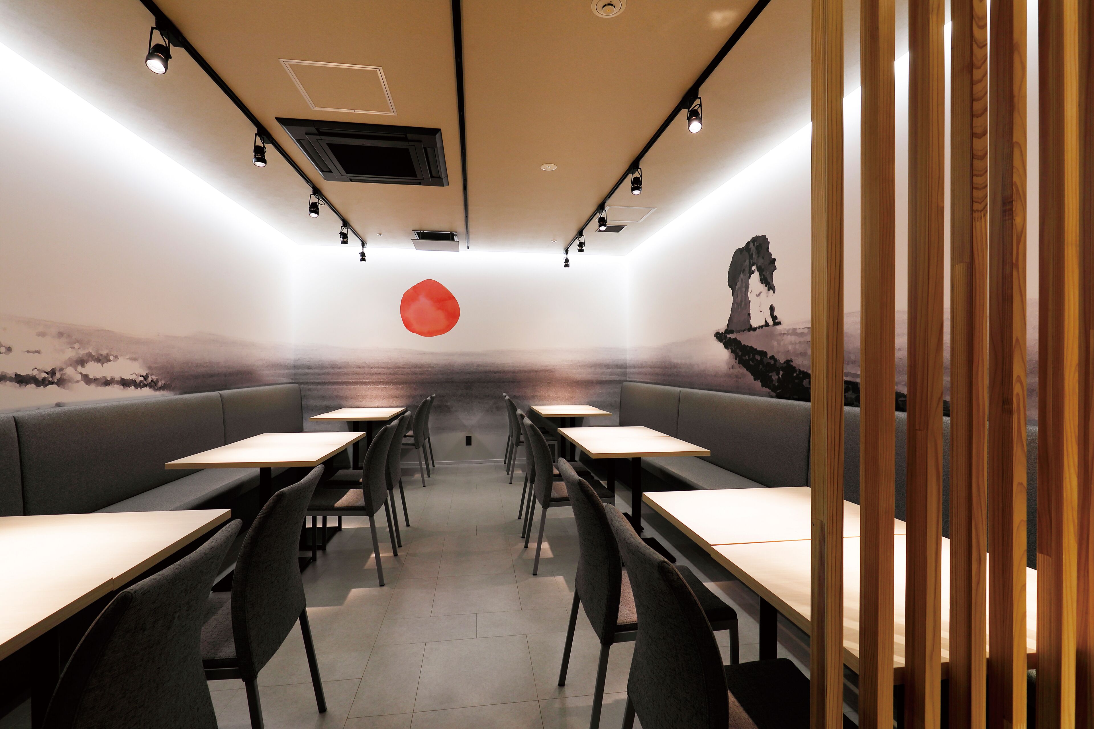 Un interior de restaurante moderno con cabinas y mesas, una decoración circular roja en el centro, y un mural en la pared del fondo.