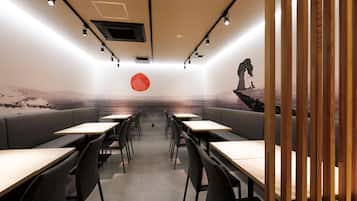 Un interior de restaurante moderno con cabinas y mesas, una decoración circular roja en el centro, y un mural en la pared del fondo.