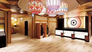 A hotel lobby with a traditional design, featuring a reception desk, patterned floor tiles, and decorative hanging lamps. - Daiwa Roynet Hotel Kanazawa Miyabi (Kanazawa)