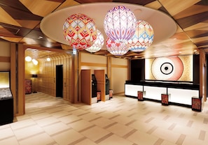 Un vestíbulo de hotel de diseño tradicional, con mostrador de recepción, baldosas de suelo estampadas y lámparas decorativas colgantes.