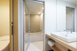 Un baño moderno con ducha envuelta en vidrio, un lavabo blanco y un espejo encima.