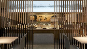 Un restaurant amb vistes a muntanyes cobertes de neu, separadors de fusta i diferents plats exposats al taulell.