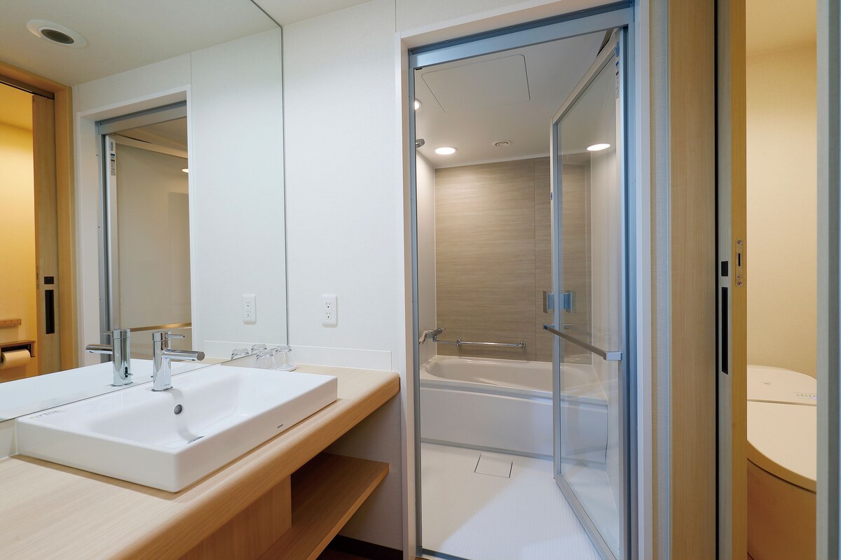 Une salle de bain moderne avec un grand miroir, deux lavabos et une douche à parois de verre.
