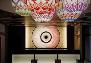 Zona de recepción con un gran diseño circular iluminado en la pared, luces esféricas decorativas en el techo y un mostrador de recepción.