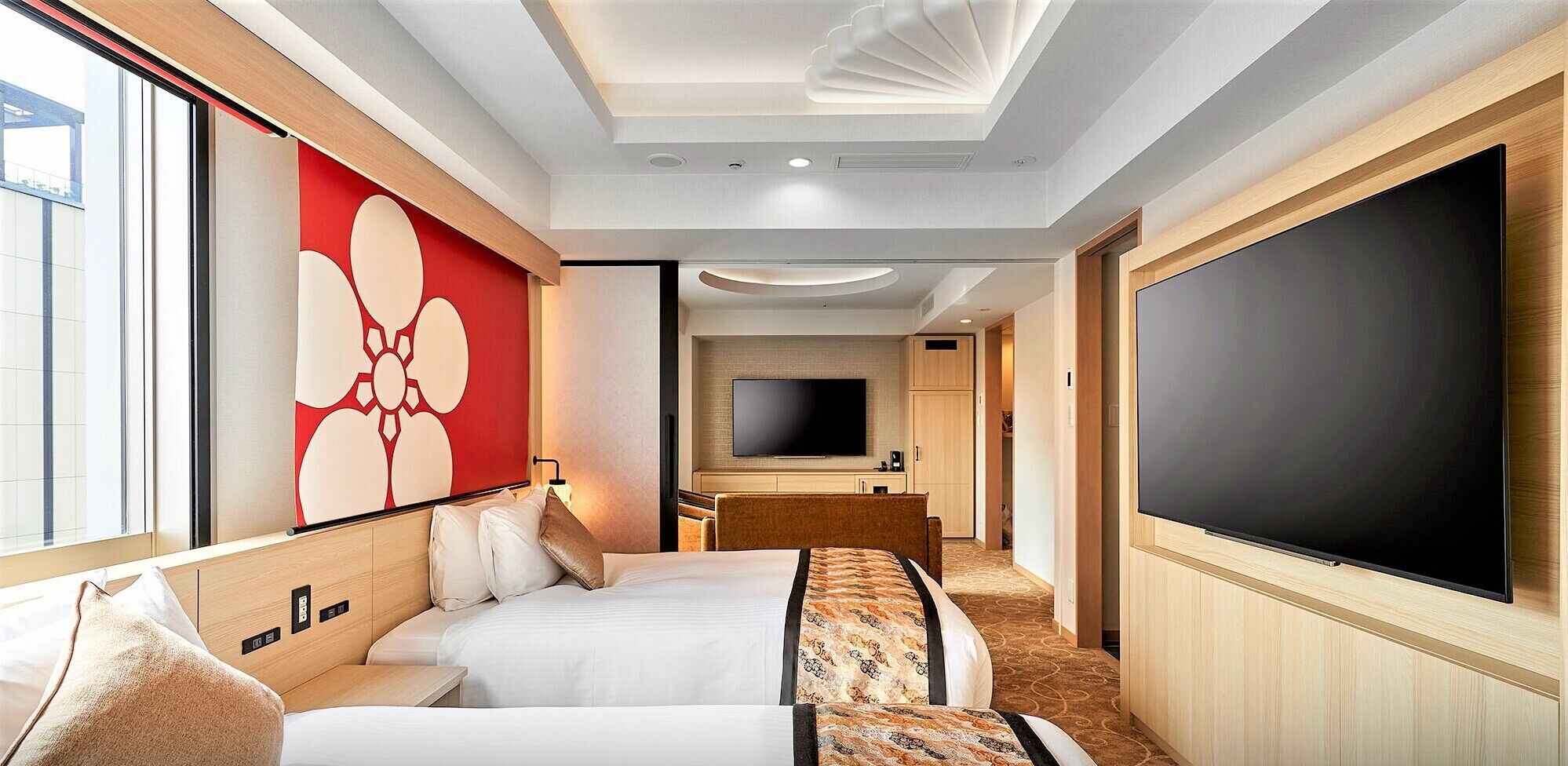 Una habitación de hotel con una cama, un televisor, un espejo grande y un adorno rojo en la pared.