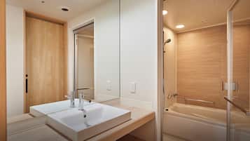 Een moderne badkamer met een grote spiegel, een witte wastafel en een inloopdouche.