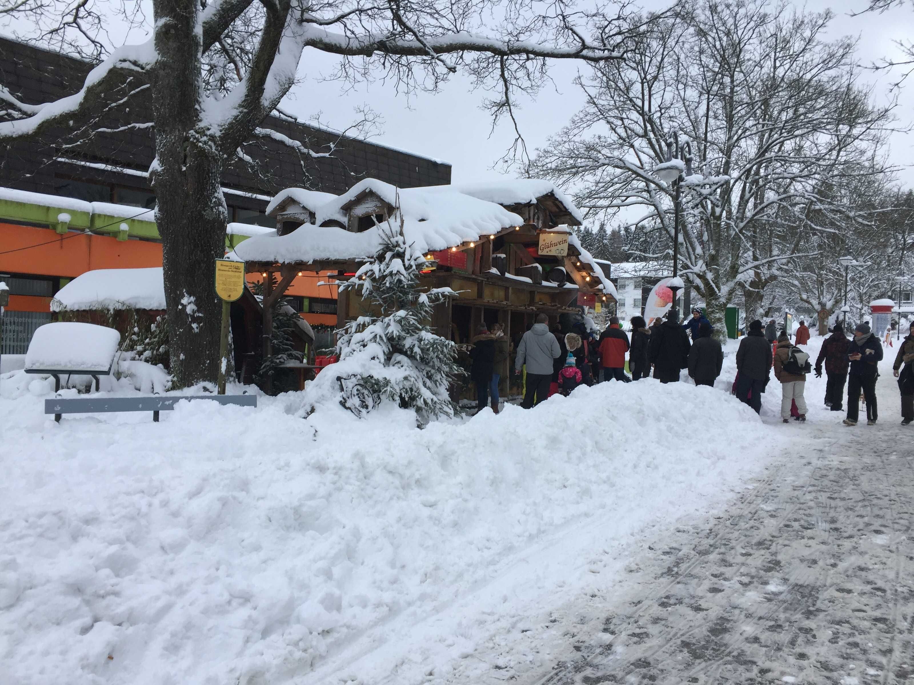 A snow-covered outdoor market with wooden stalls and a bench.
