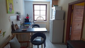 A compact kitchen with a refrigerator, a window, and a dining area with chairs.