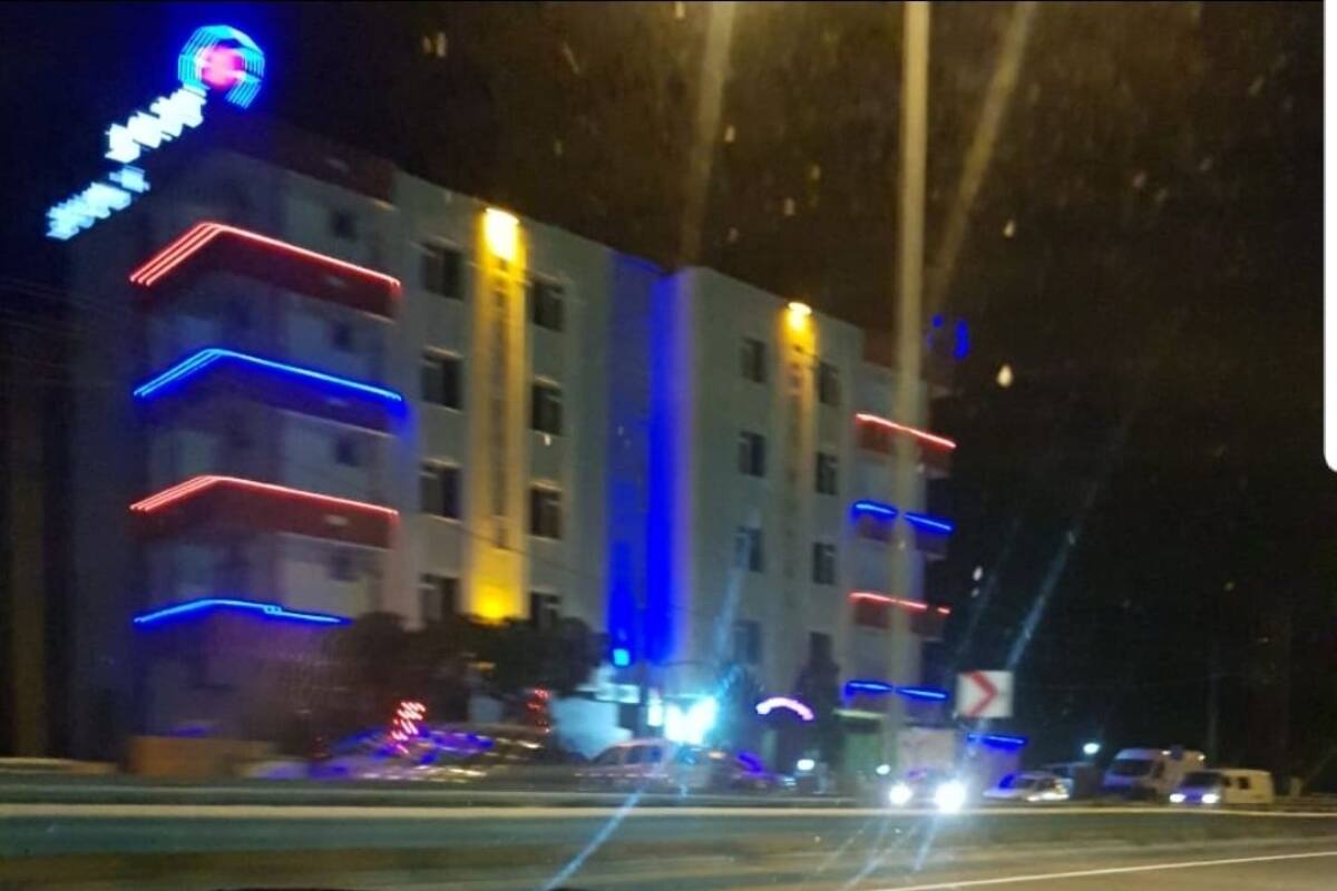 A multi-story building with illuminated balconies and a prominent sign on the left.