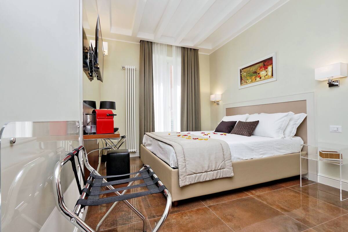 A hotel room with a bed, a desk, a chair, and a window with curtains.