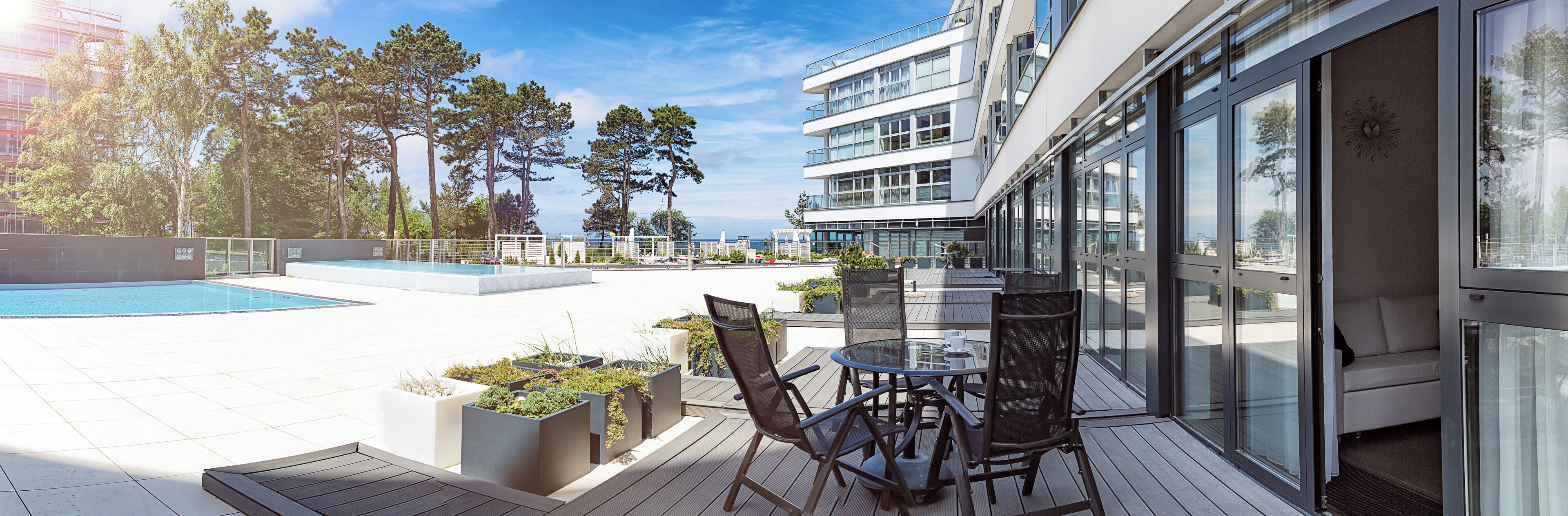 A rooftop terrace with a swimming pool, outdoor seating, and a view of the city skyline.