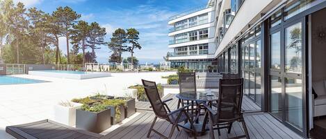 A rooftop terrace with a swimming pool, outdoor seating, and a view of the city skyline.