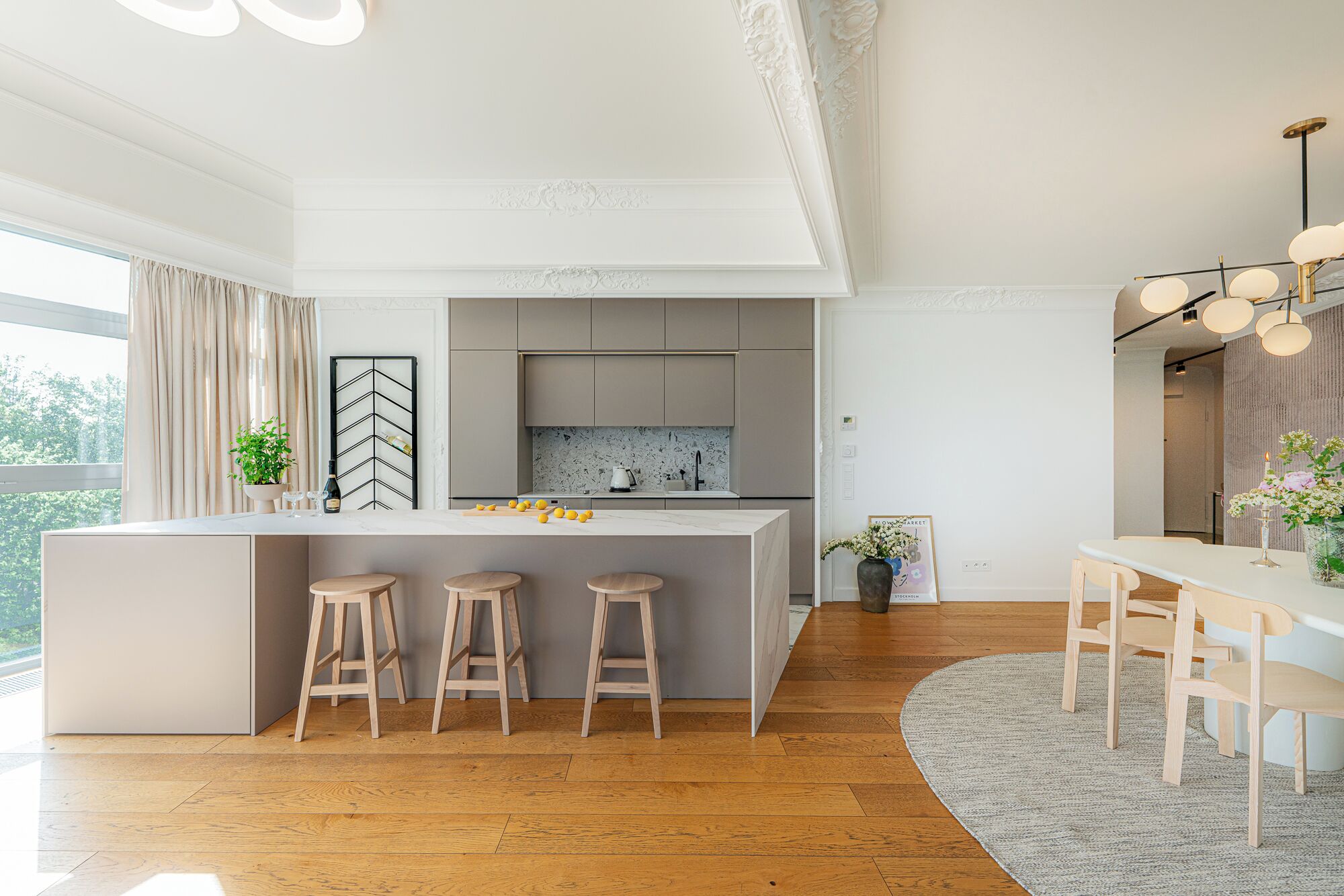 A modern kitchen with a central island, bar stools, and a dining area with a table and chairs.