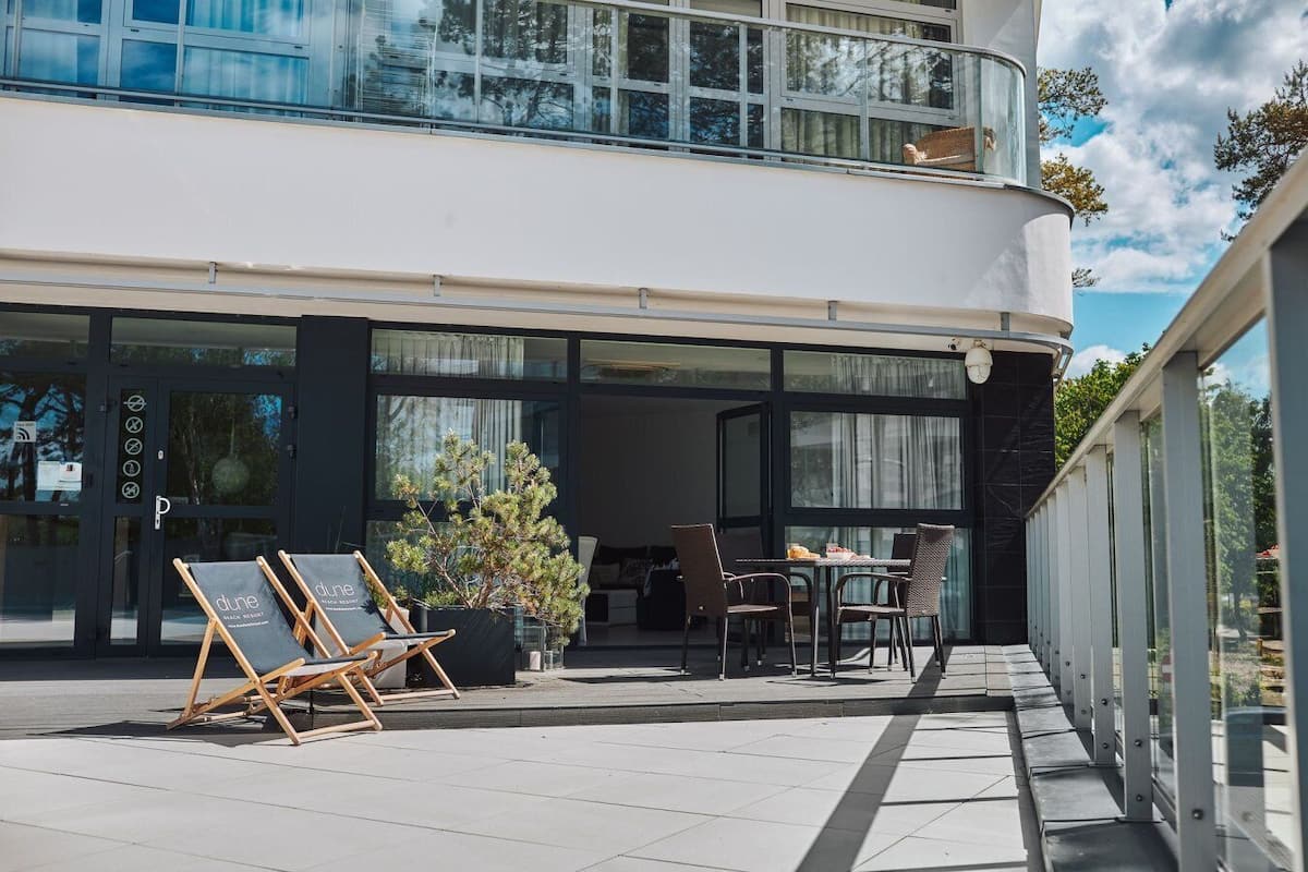 Un edificio moderno con balcón, asientos al aire libre y un cartel.