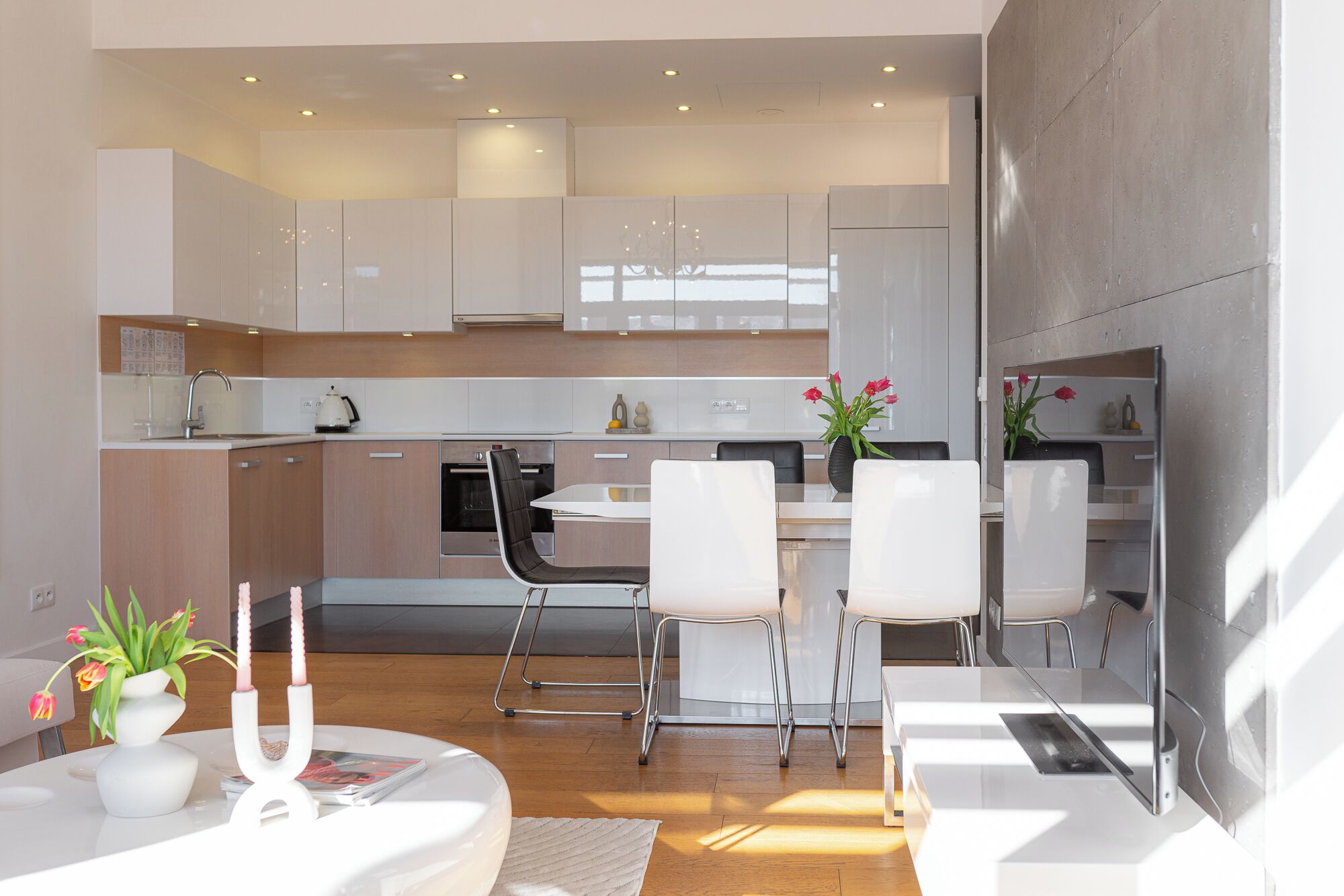A modern kitchen with white cabinets, a dining area with white chairs, and a central island.