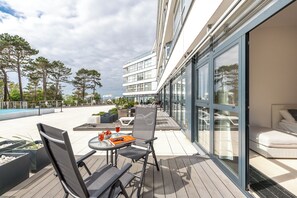 Un balcón moderno al aire libre con una mesa de comedor, sillas y un sofá.