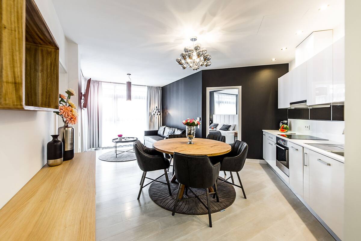 Una cocina moderna con armarios blancos, una mesa redonda con sillas y una araña.