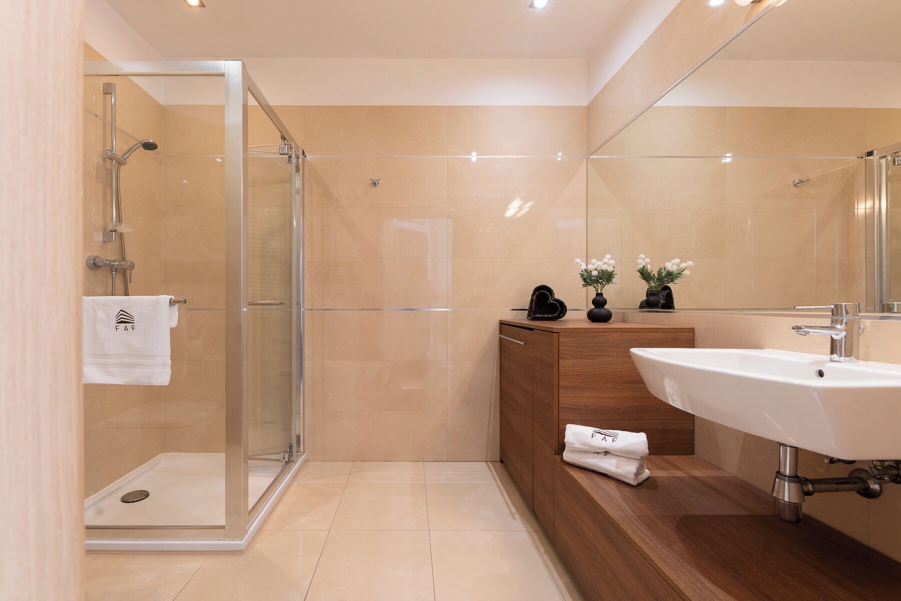 A modern bathroom with a glass-enclosed shower, a wooden vanity with a sink, and a mirror.