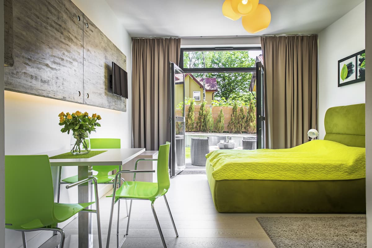 Una habitación moderna con cama, una mesa de comedor con sillas, un televisor montado en la pared y vistas al exterior.