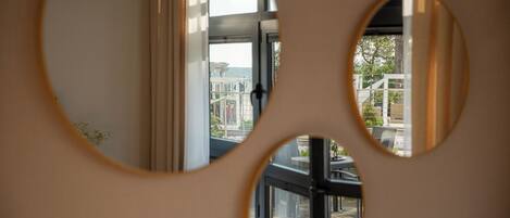 A view through circular cutouts in a wall, revealing a balcony with outdoor furniture and a railing.