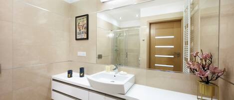 Een moderne badkamer met een grote spiegel, een witte wastafel en een badmeubel met lades.