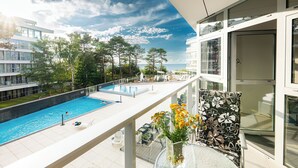 Un balcon donnant sur une piscine, une porte vitrée et une chaise à motifs floraux.