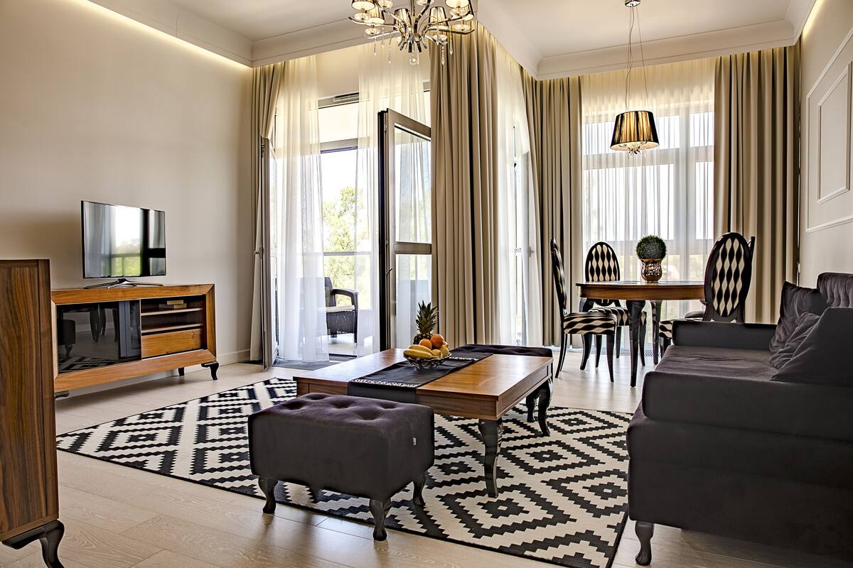 Una sala de estar moderna con una televisión de pantalla plana, una mesa de centro de madera, un sofá y un comedor con sillas y una mesa.