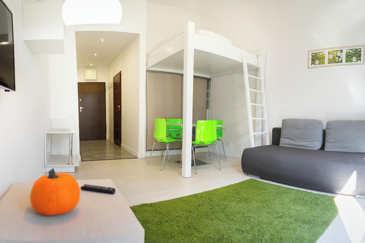 Una sala de estar moderna con un sofá, sillas verdes, una escalera y un televisor.