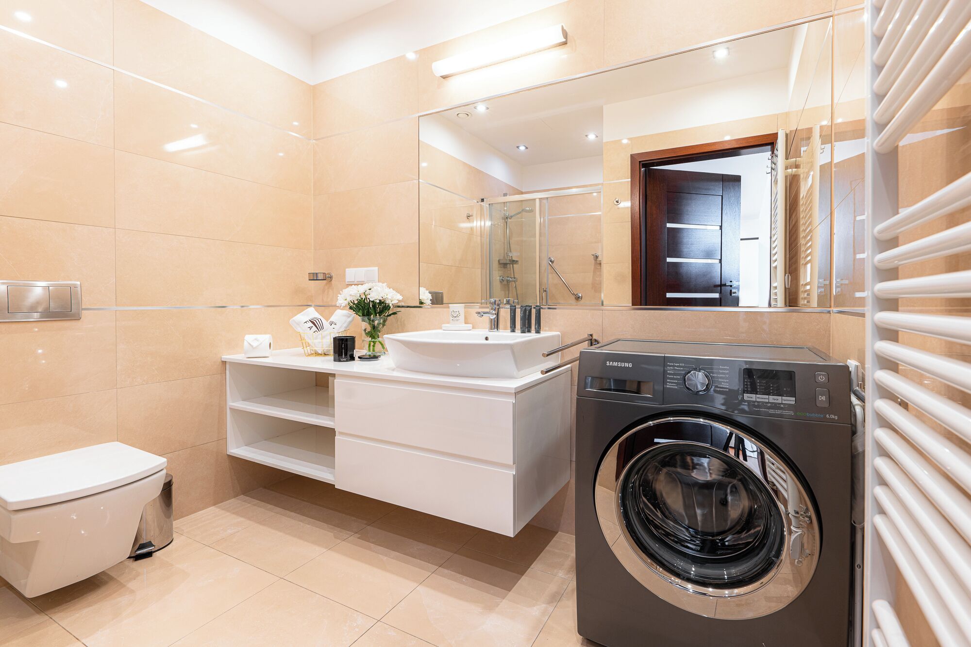 A modern bathroom with a white sink, mirror, and a built-in washing machine.